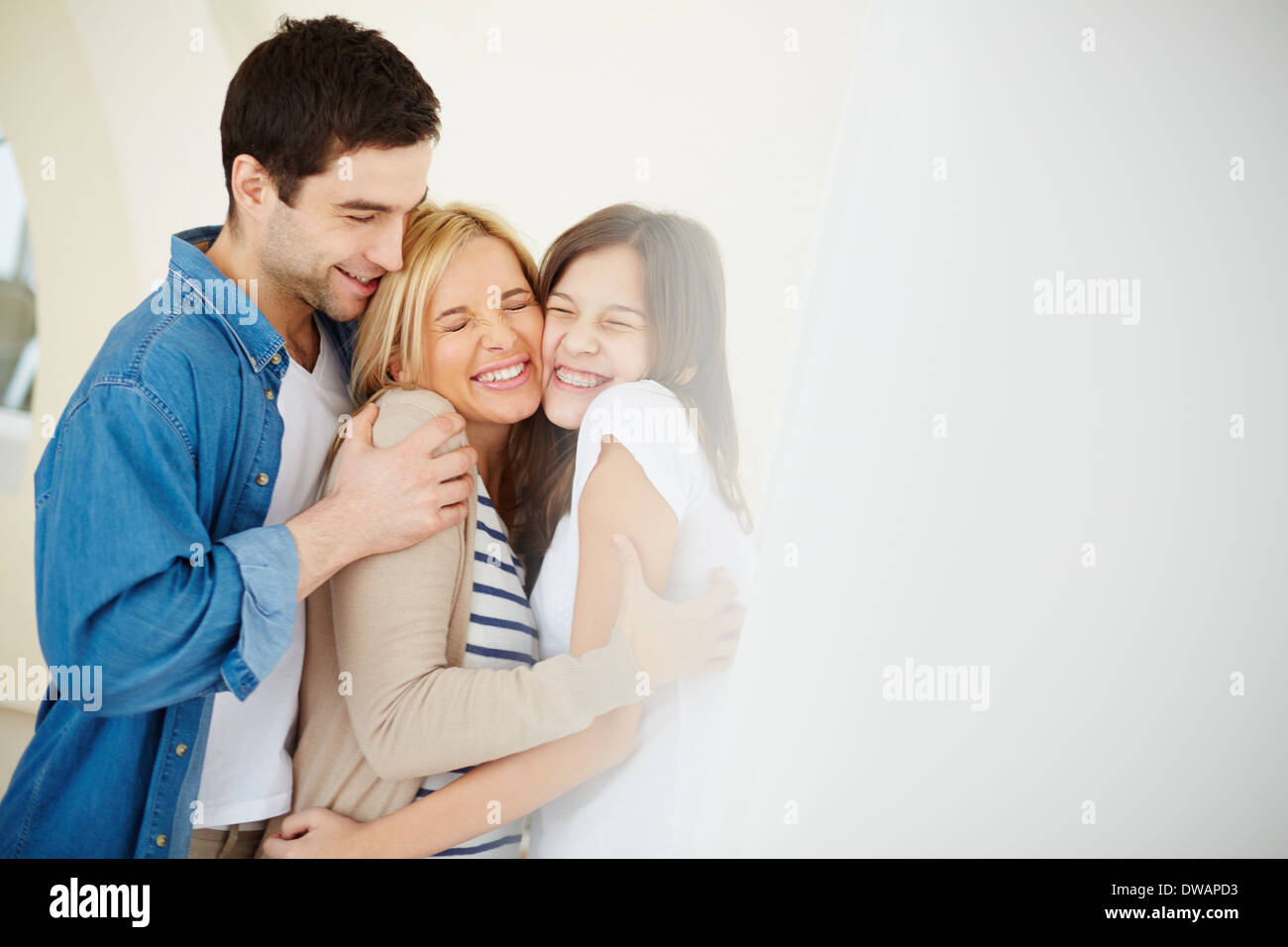 Portrait of joyful family of three in embrace Stock Photo
