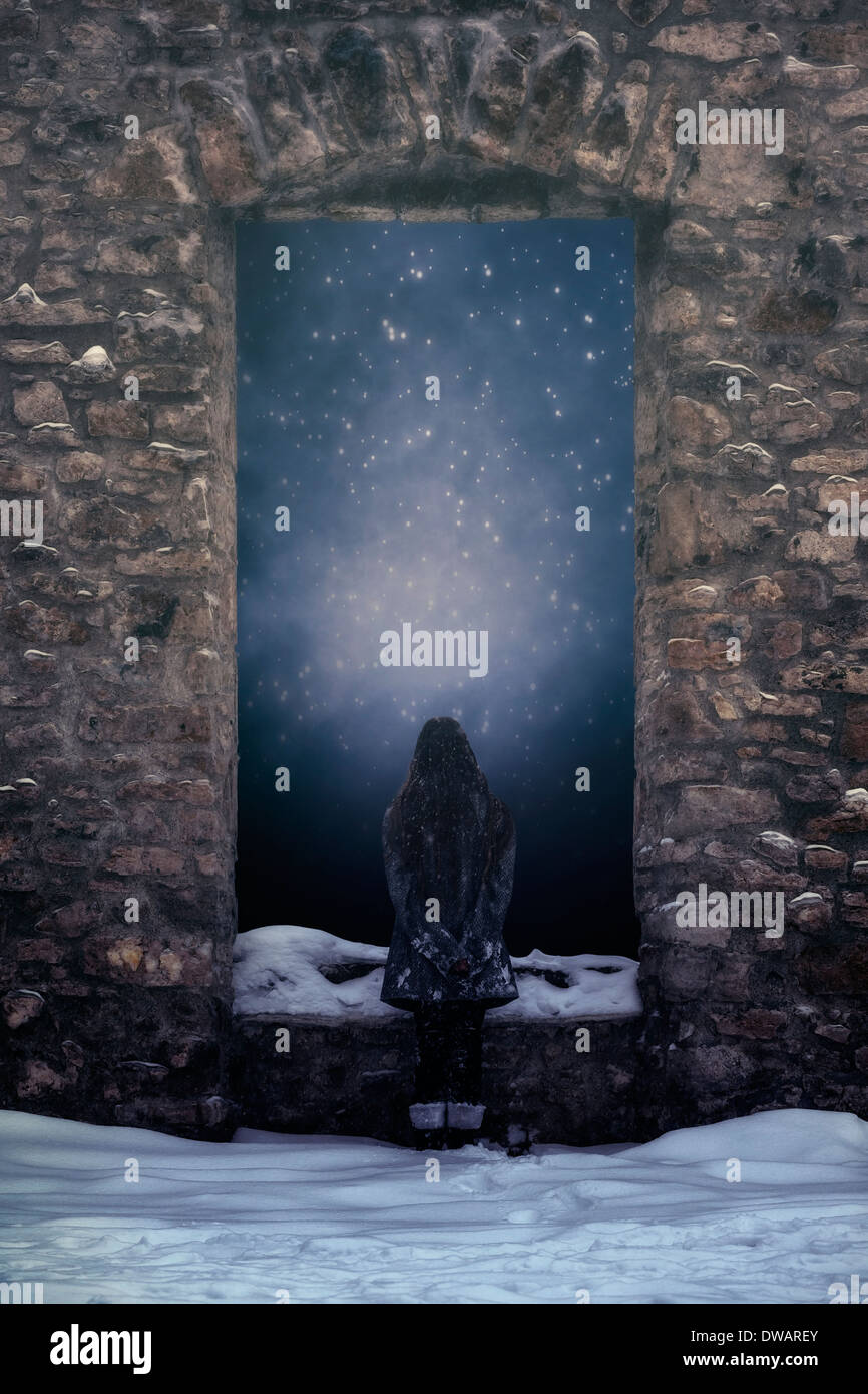 a girl is standing in front of a window of an old castle in the snow Stock Photo