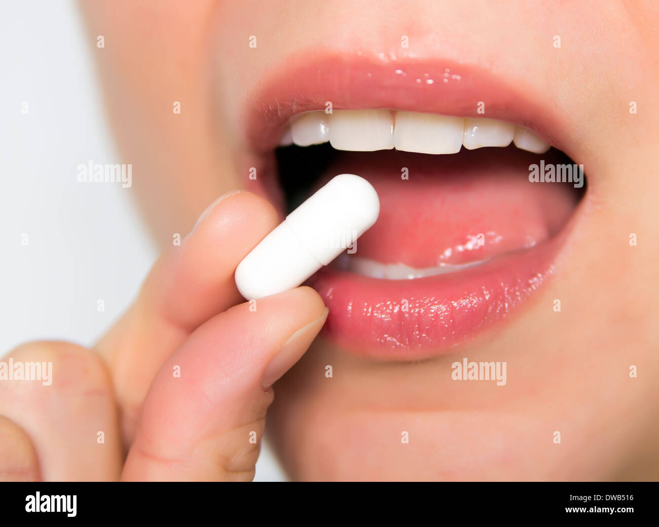 young woman taking white pill Stock Photo