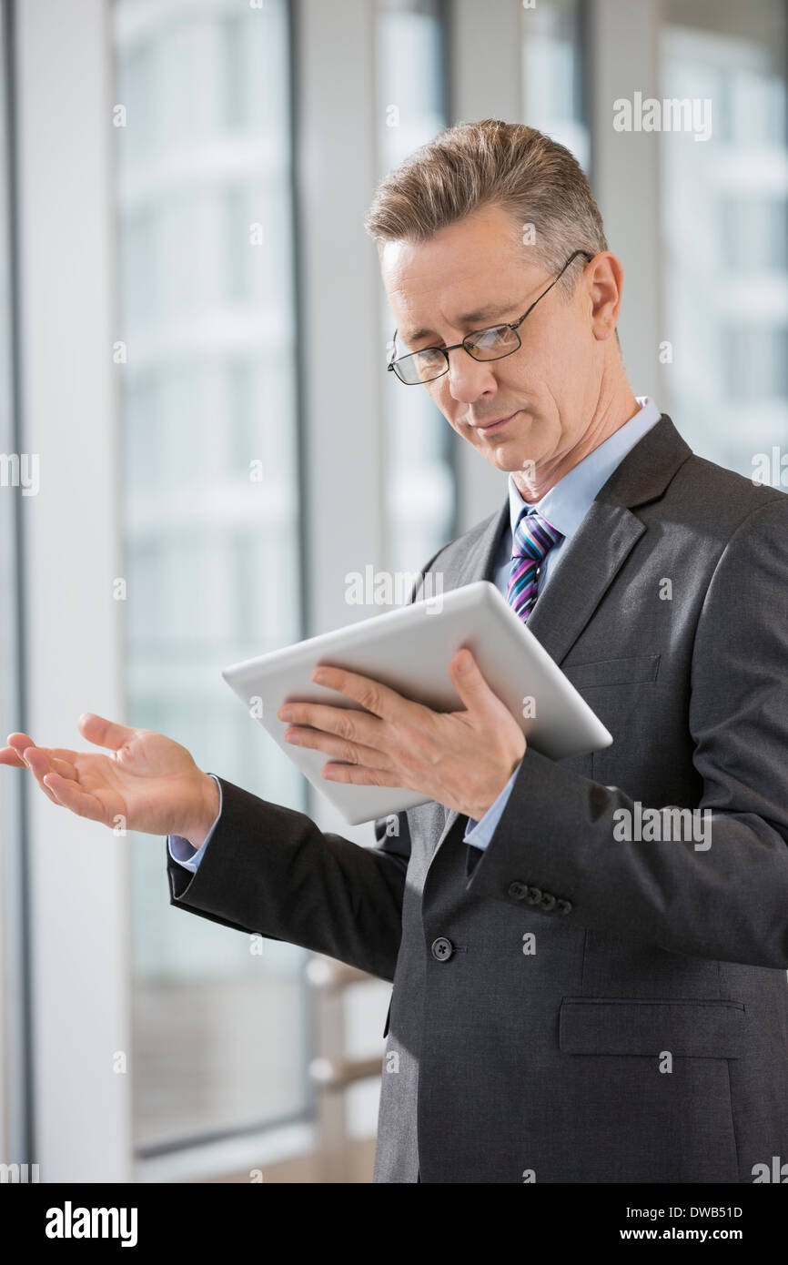 Businessman gesturing while using tablet PC in office Stock Photo