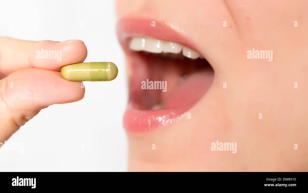 young woman taking the pill, focus on pill Stock Photo