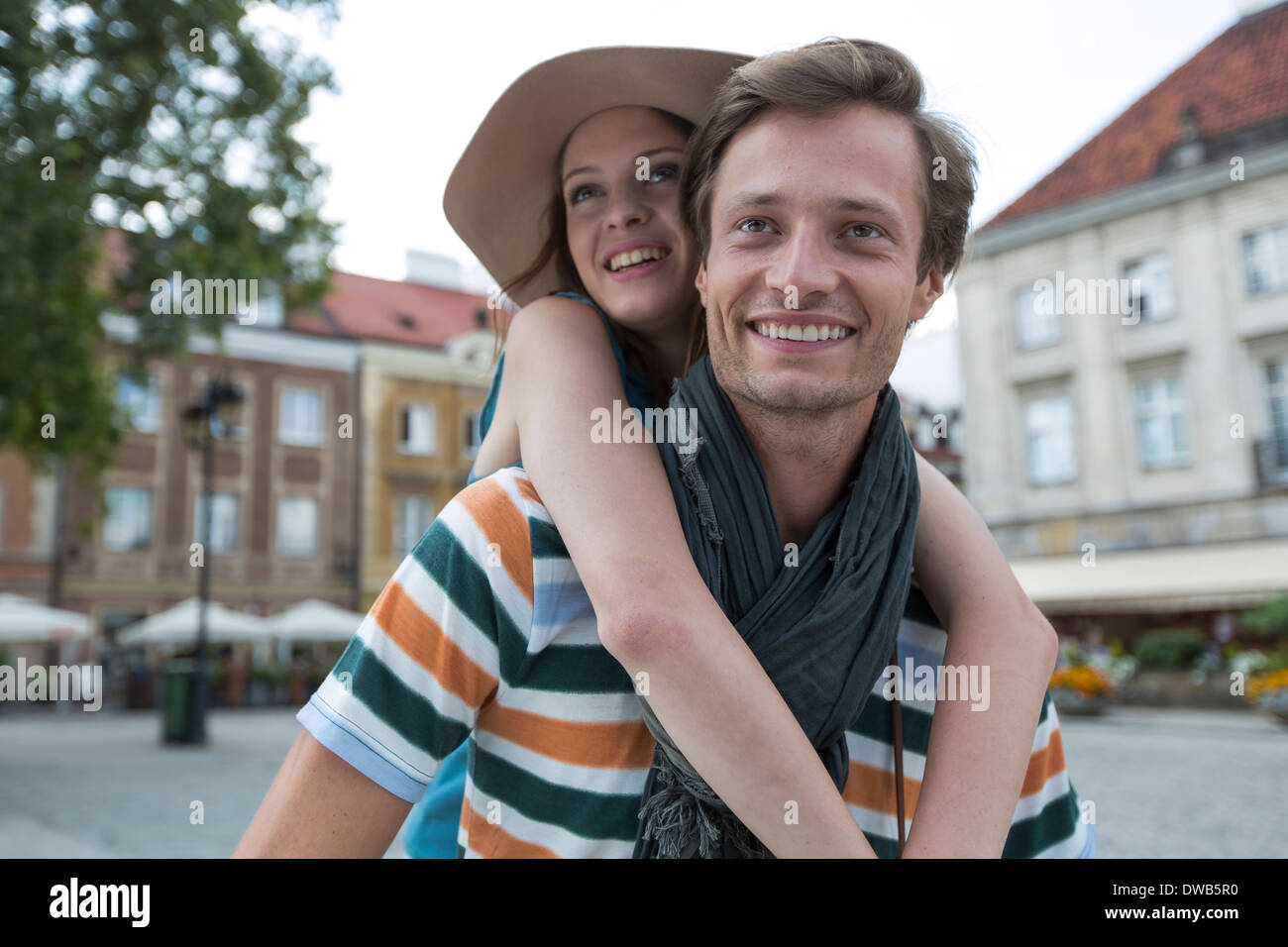 Happy man piggybacking woman on street during vacation Stock Photo
