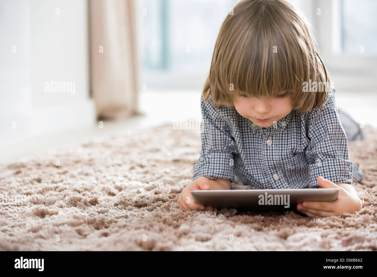 Boy using digital tablet while lying on rug at home Stock Photo - Alamy