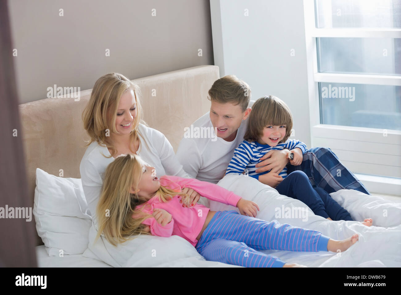 Parents playing with children in bedroom Stock Photo