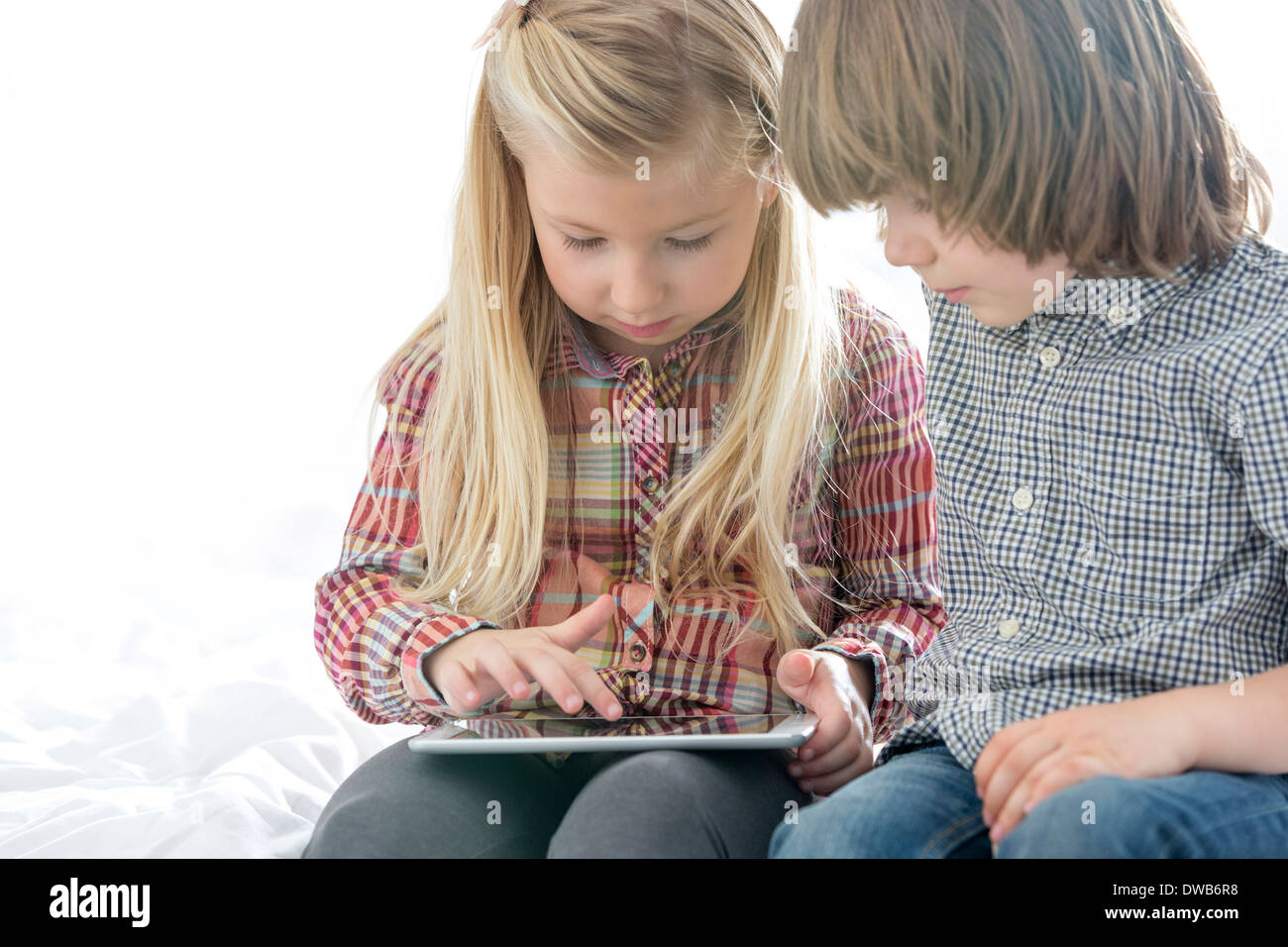 Brother and sister using tablet PC in bedroom Stock Photo