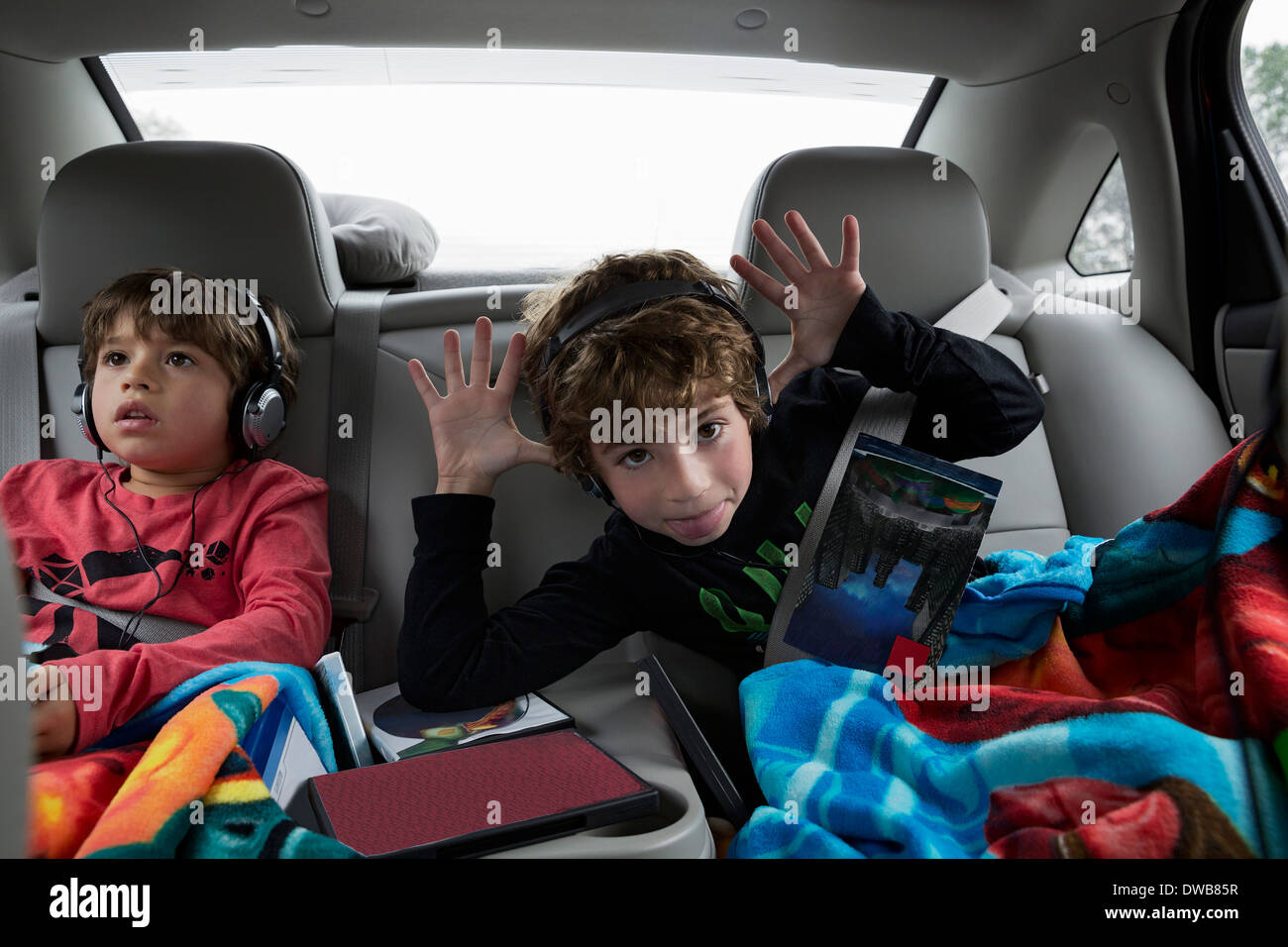 Brothers in back seat of car, wearing headphones Stock Photo