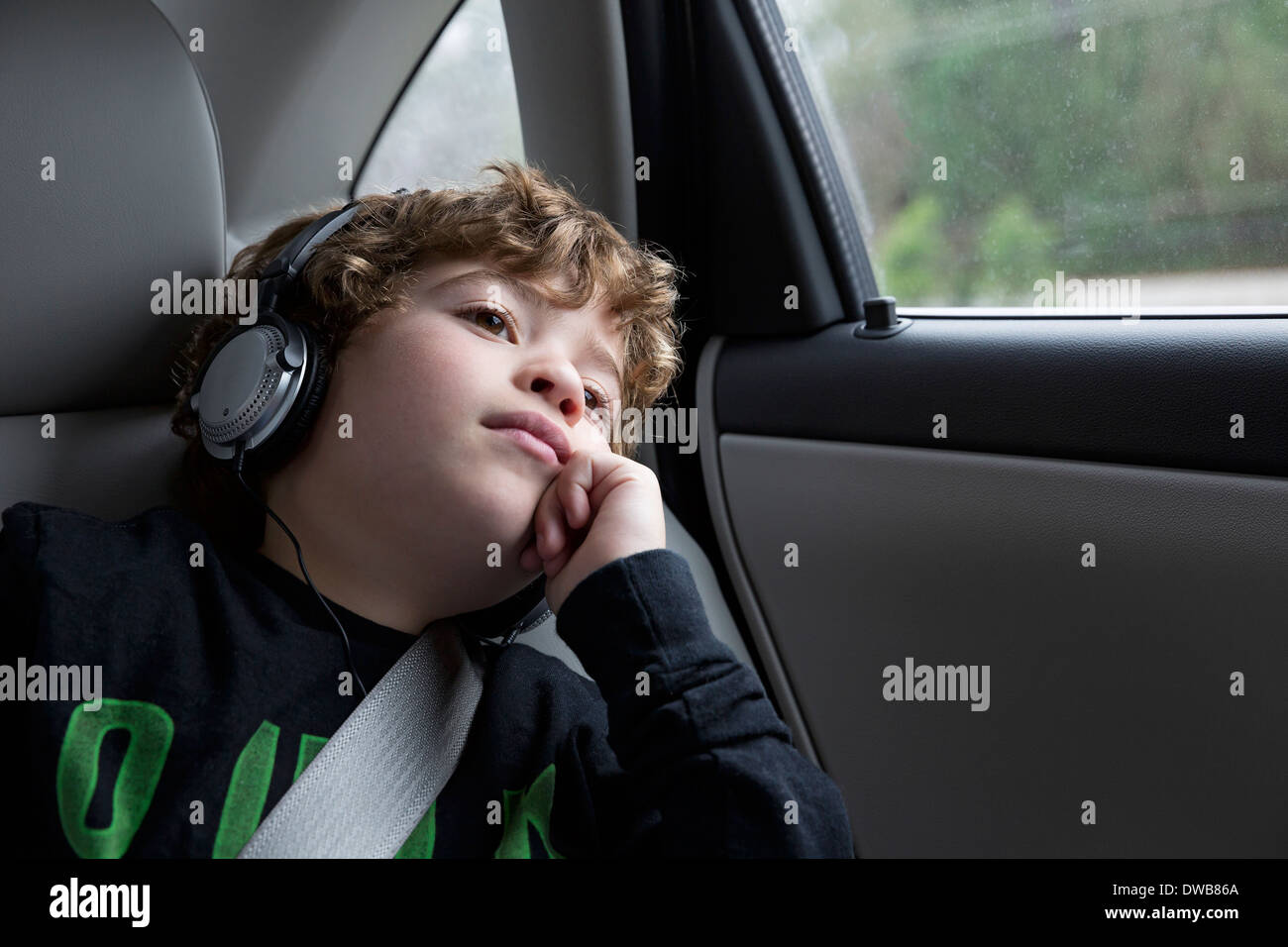 Boy in back seat of car, wearing headphones Stock Photo