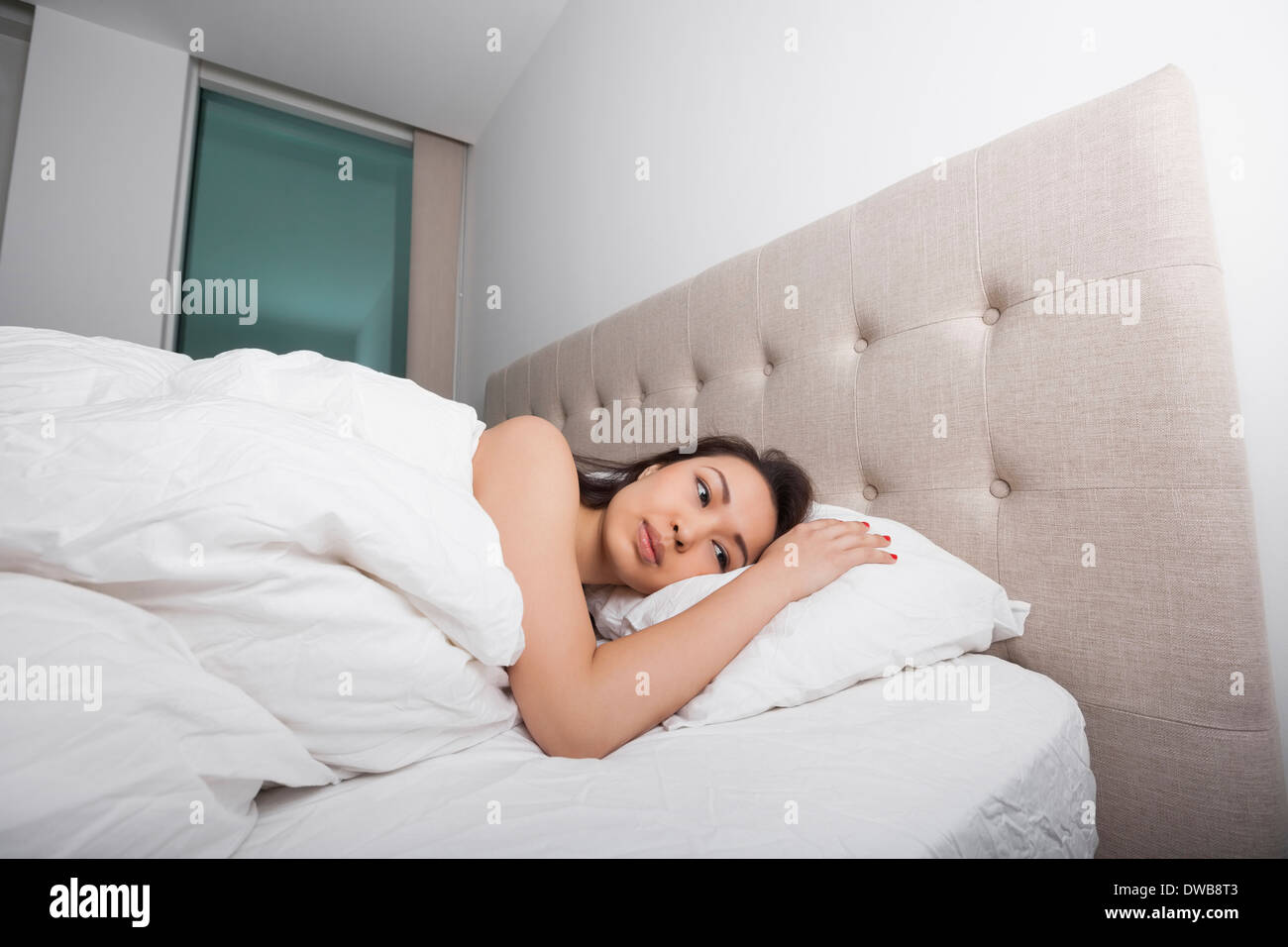 Thoughtful young woman lying in bed Stock Photo