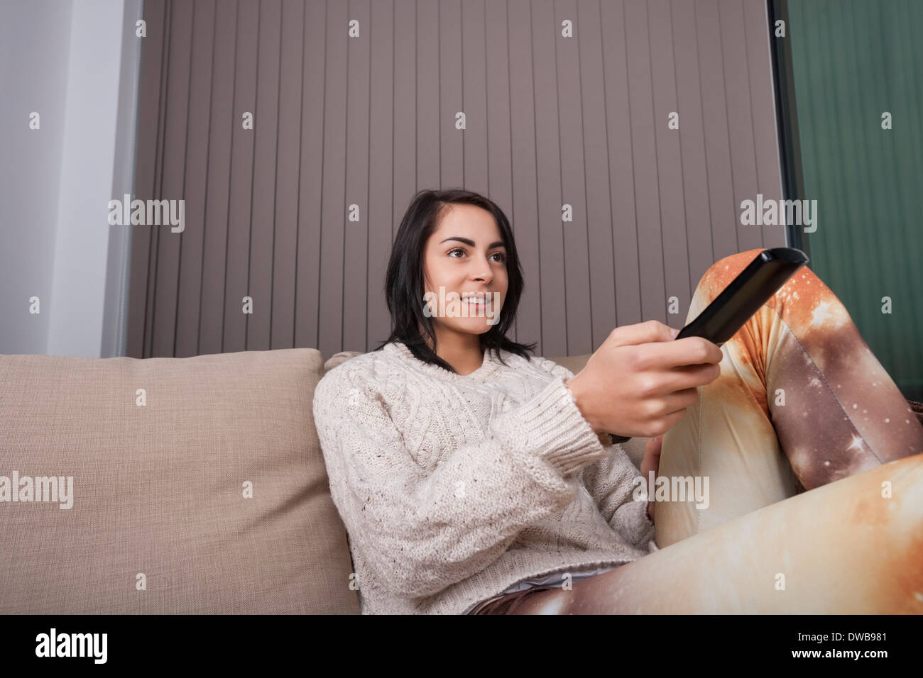 Young woman watching TV in living room Stock Photo