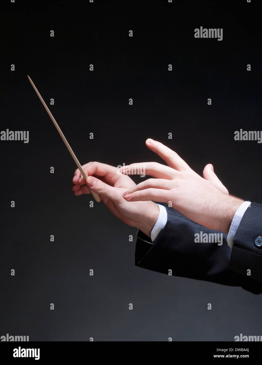 Hands of Conductor with Baton Leading Orchestra Stock Photo