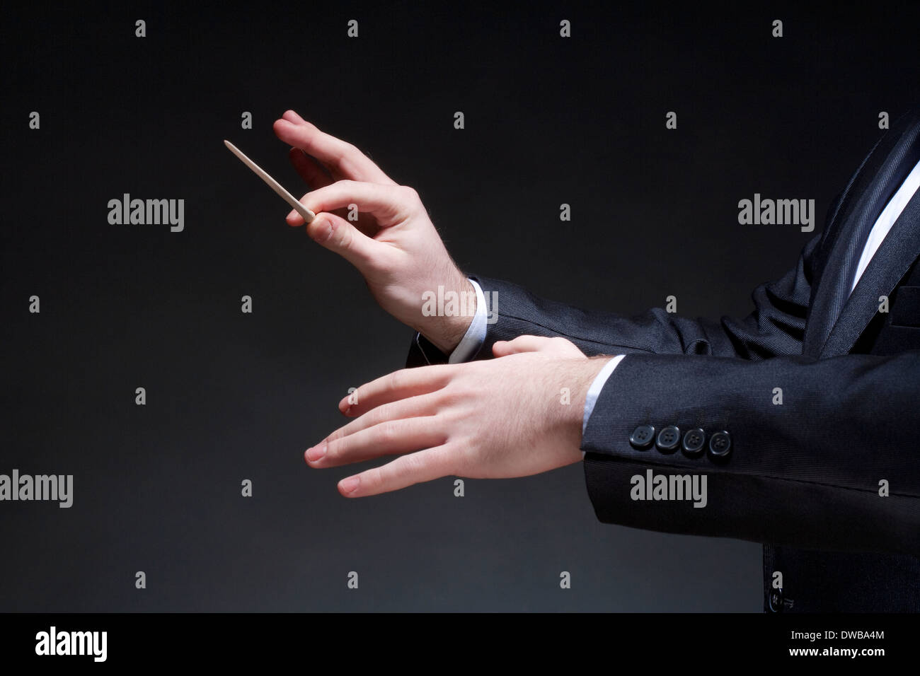 Hands of Conductor with Baton Leading Orchestra Stock Photo