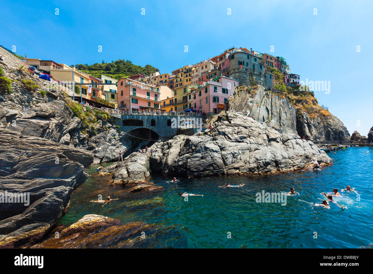 Italy, Liguria, La Spezia, Cinque Terre, Manarola, view to village, bathing people in front Stock Photo