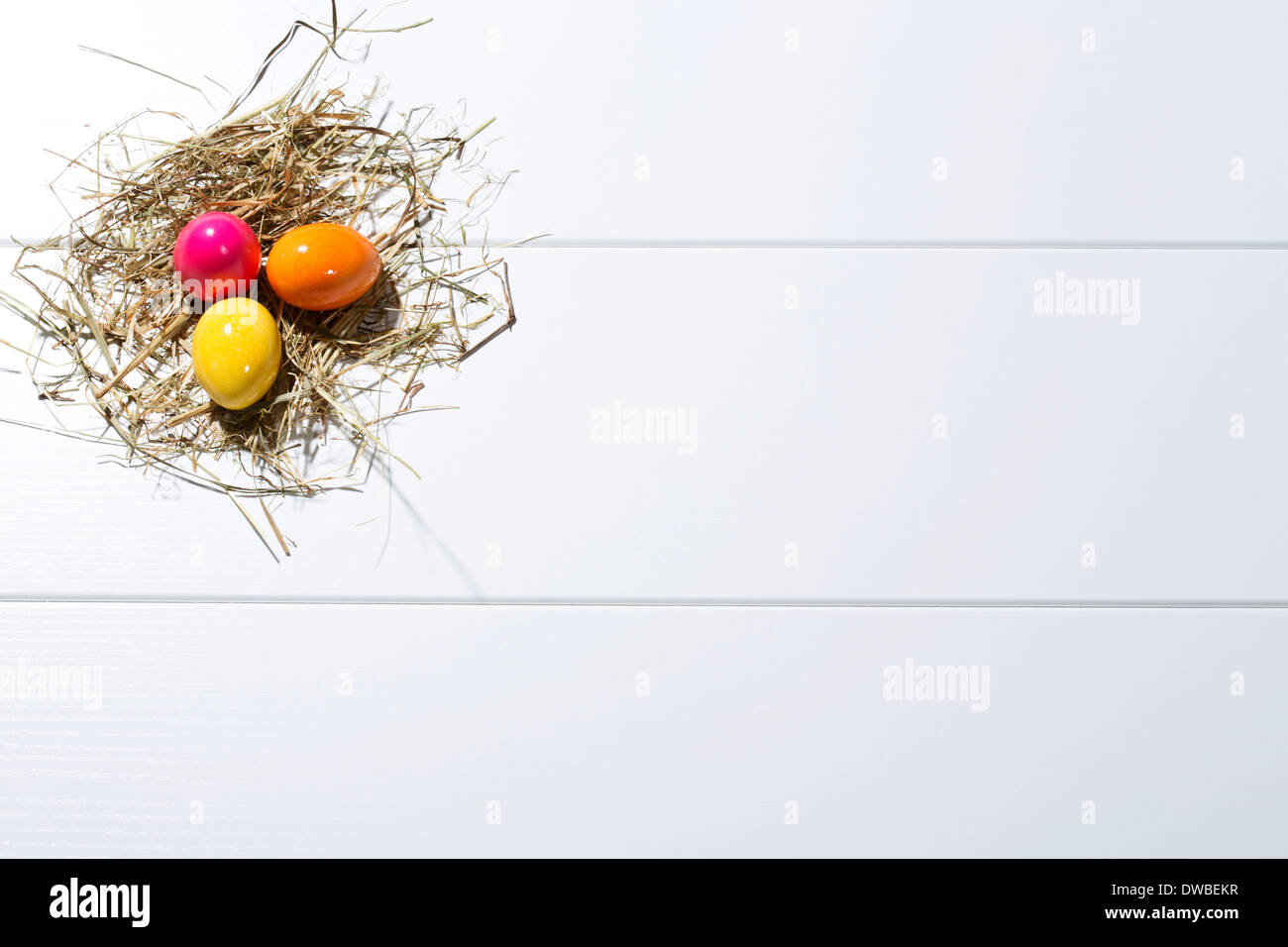 Three coloured Easter eggs and straw on white ground Stock Photo - Alamy