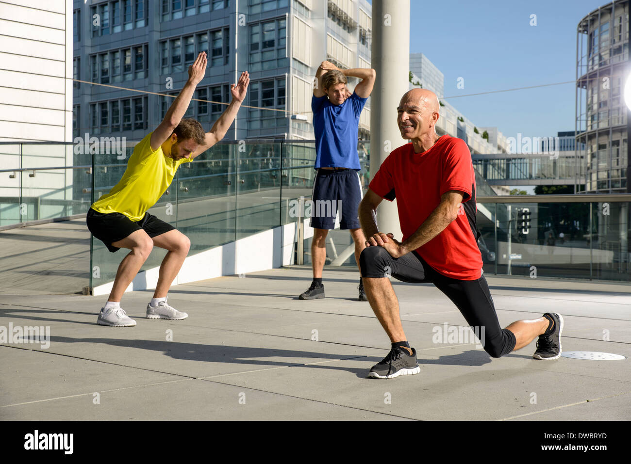 Three male athletes exercising on city rooftop Stock Photo