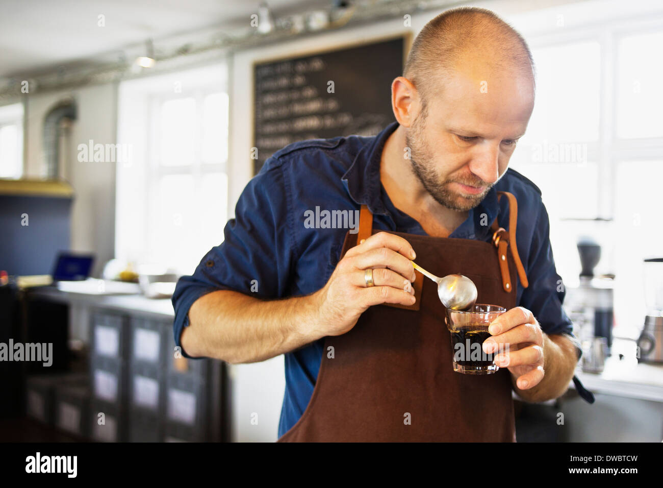 Male barista stirring coffee glass in coffee bar Stock Photo