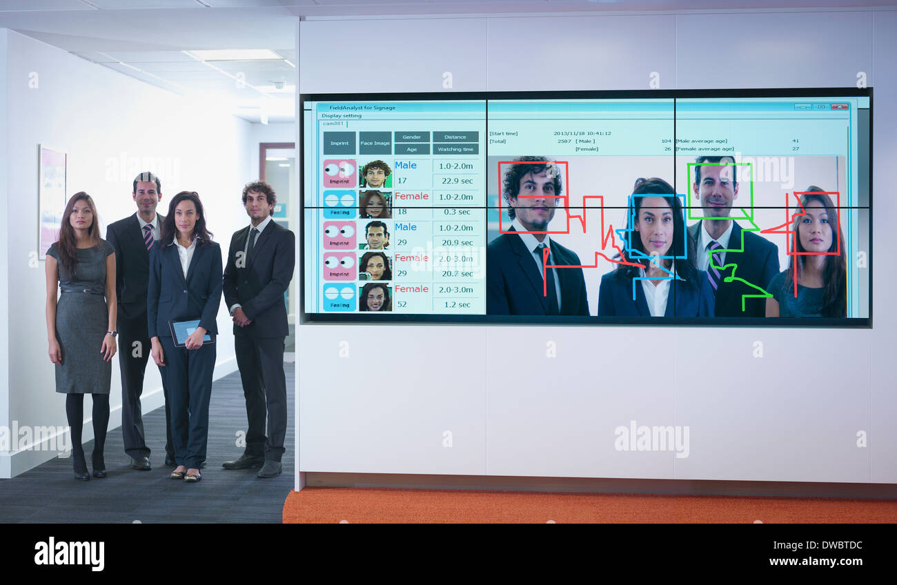 Portrait of office workers standing next to face recognition software system Stock Photo