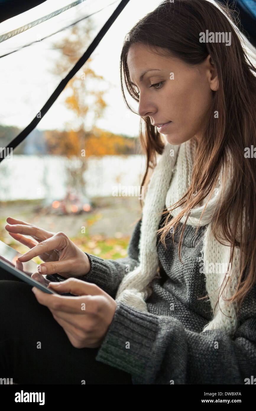 Young woman using digital tablet in tent Stock Photo