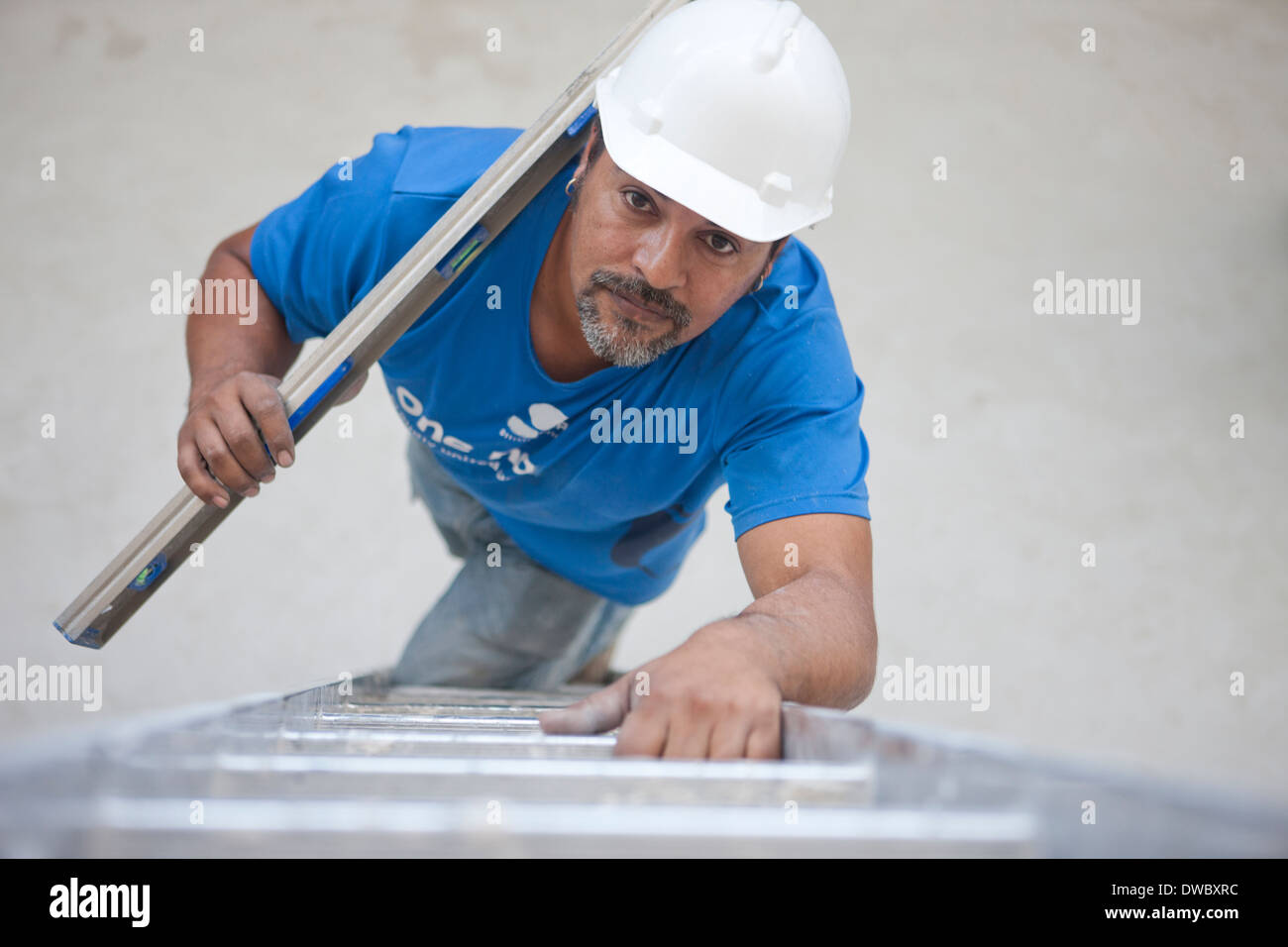 Builder with metal rod climbing ladder Stock Photo