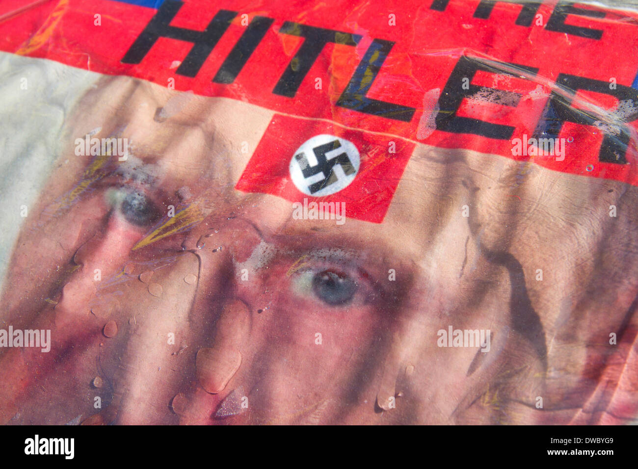 Westminster London ,UK. 5th March 2014. A portrait of Russian president Putin portrayed as Hitler with a German swastika. Ukrainian protesters continue to hold a 24hour shift protest outside Downing Street with placards following the Russian military intervention in the Crimea demanding on the British Government to keep its promises on the Budapest memorandum on Security Assurances signed in 1994. Credit:  amer ghazzal/Alamy Live News Stock Photo