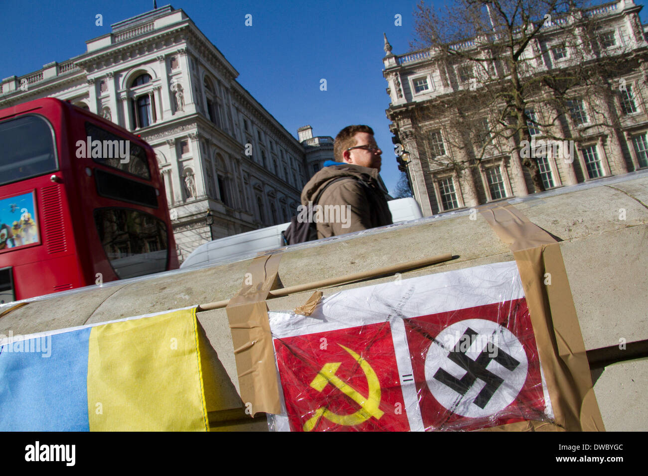 Westminster London ,UK. 5th March 2014. A man walks past banners by Ukrainian protesters who continue to hold a 24hour shift protest outside Downing Street with placards following the Russian military intervention in the Crimea demanding on the British Government to keep its promises on the Budapest memorandum on Security Assurances signed in 1994. Credit:  amer ghazzal/Alamy Live News Stock Photo