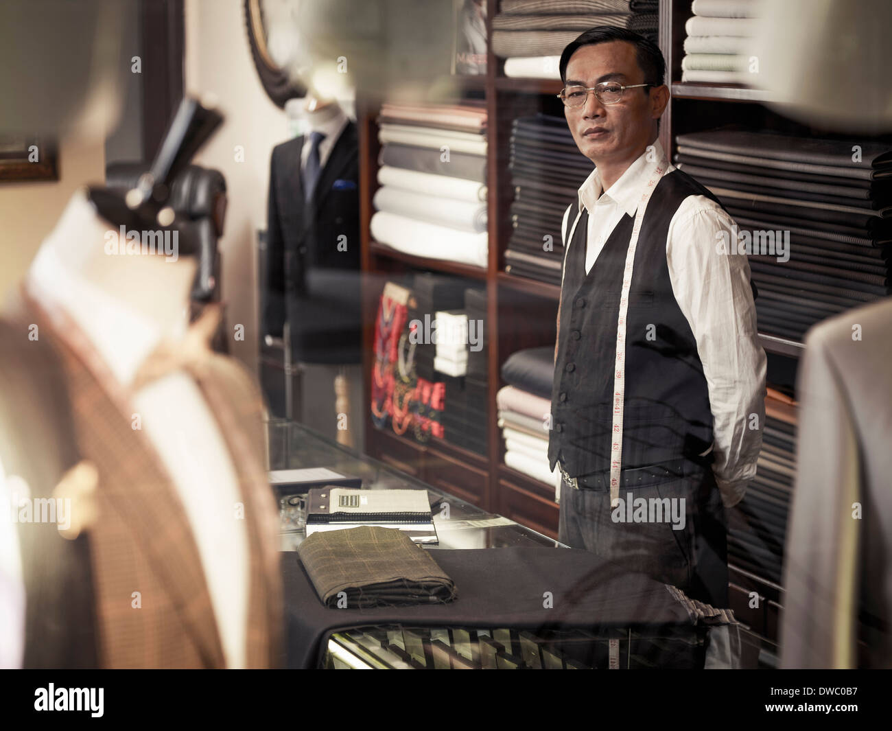 Tailor standing behind counter in tailors shop Stock Photo
