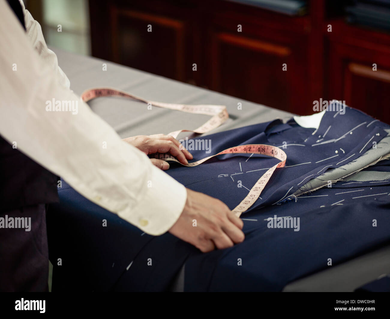Tailor measuring garment on table in traditional tailors shop Stock