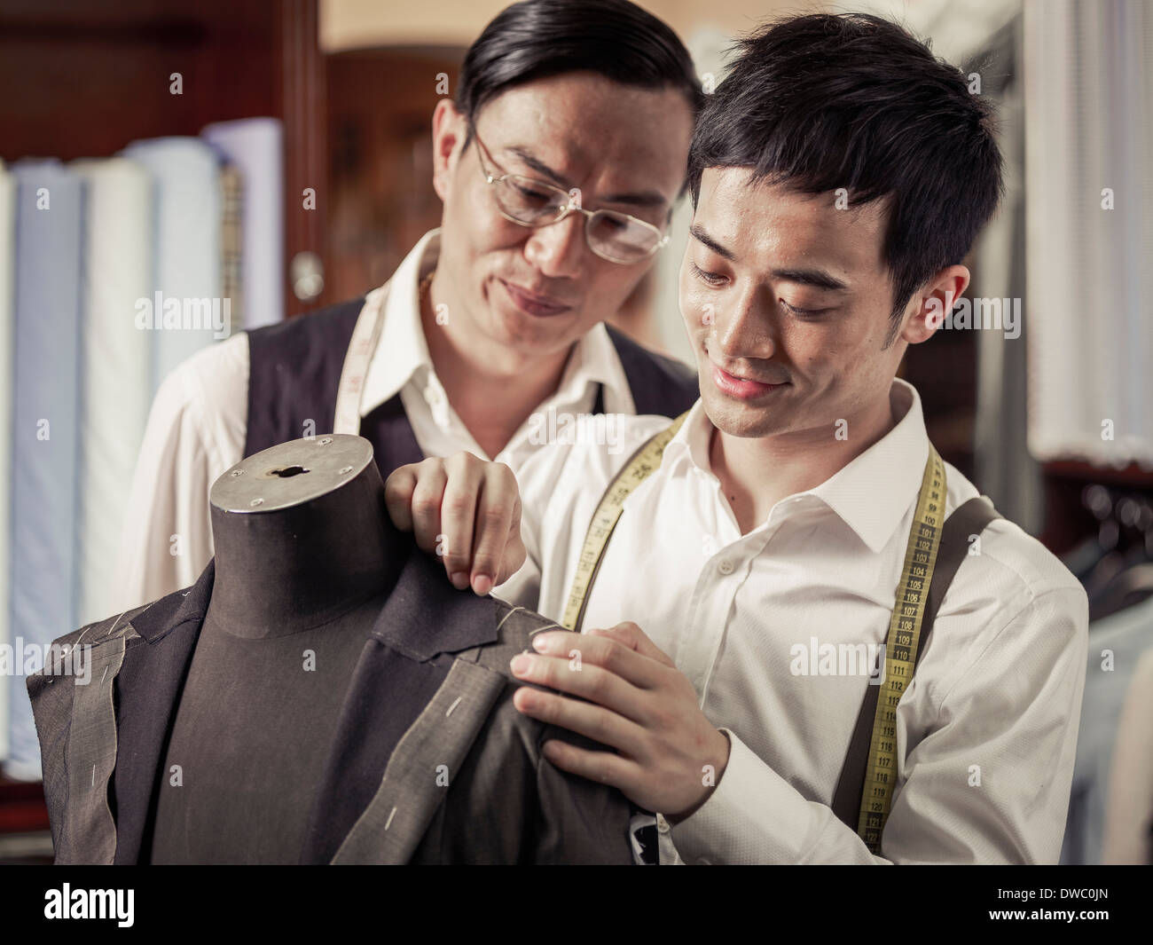 Father monitoring son in family tailoring business Stock Photo