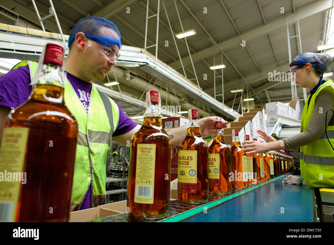 Workers on the production line check and pack whisky into cases at