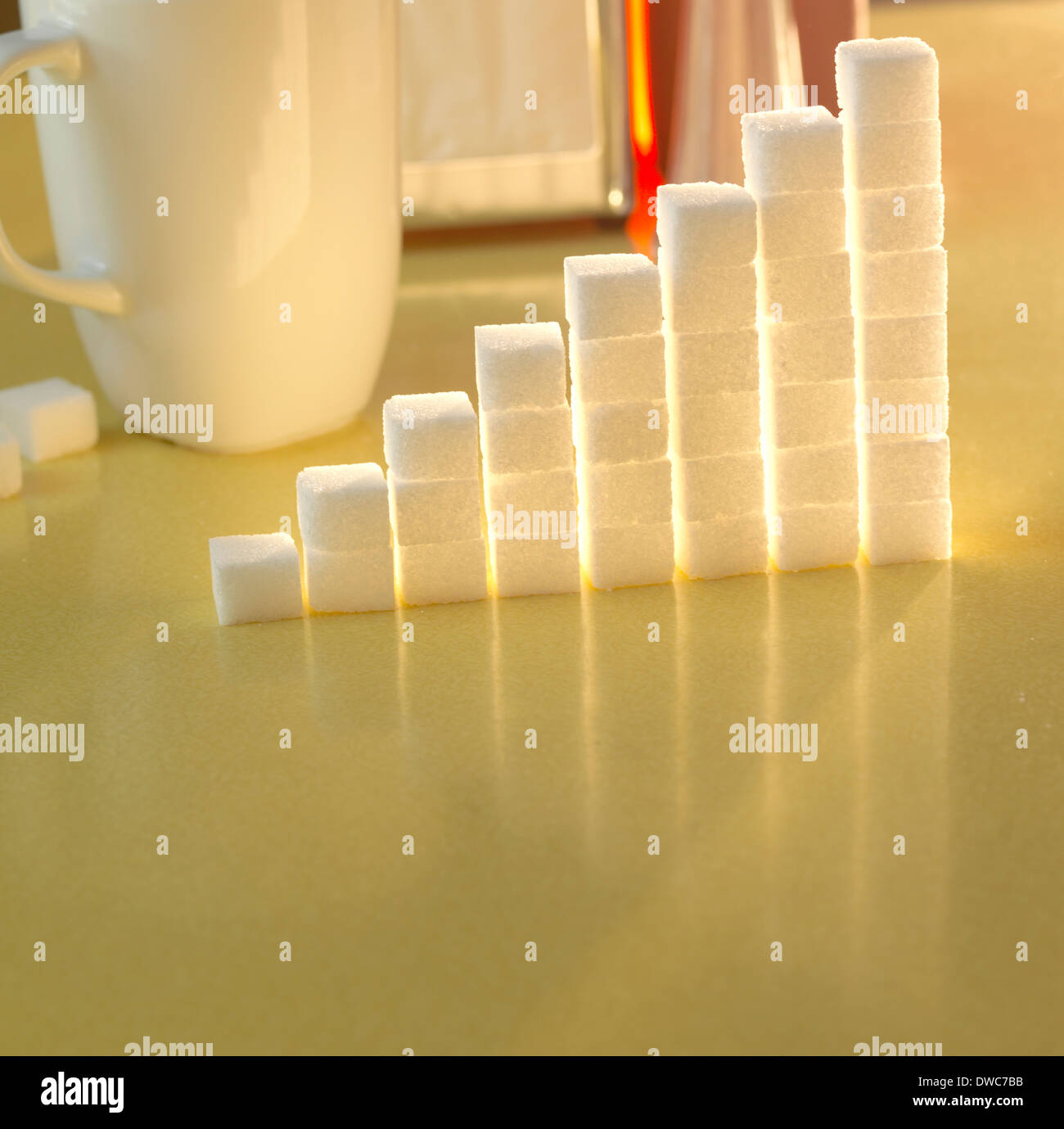 Stack of sugar cubes in the shape of a graph on a yellow table Stock