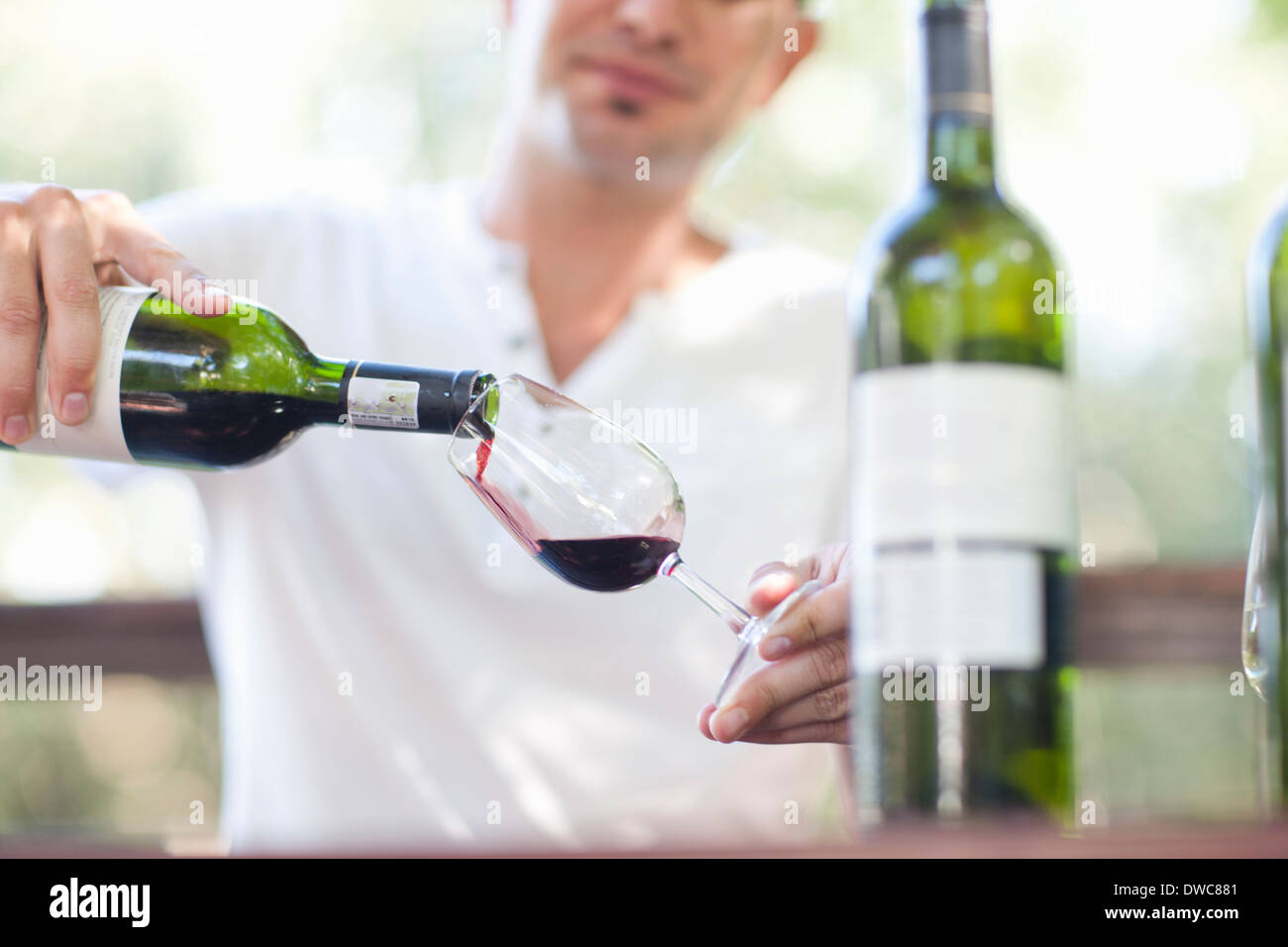 Young male waiter pouring red wine at vineyard bar Stock Photo