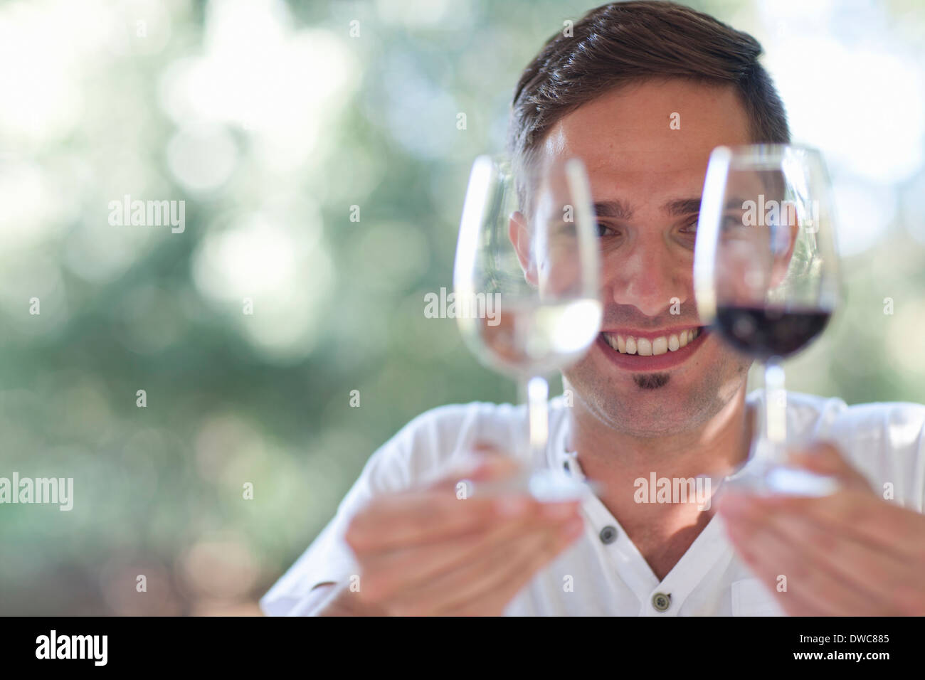 Young male waiter holding up glasses of red and white wines Stock Photo