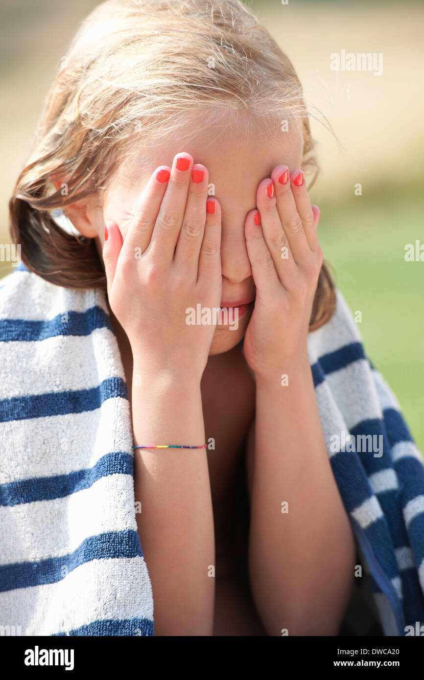 Girl wrapped in towel with her hands over her eyes Stock Photo