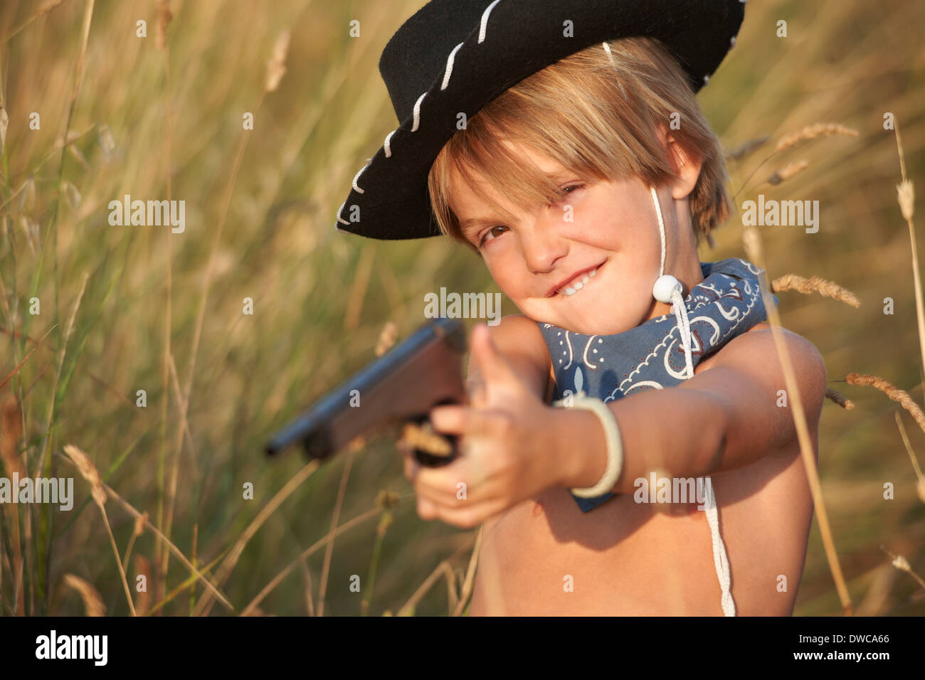 Portrait of boy in cowboy hat pointing toy gun Stock Photo