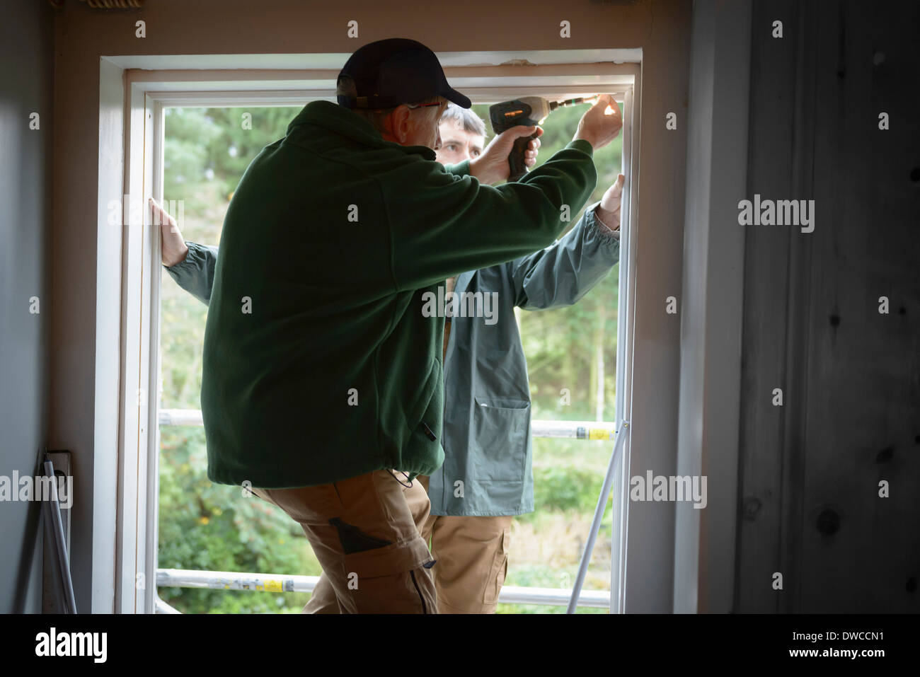 Father and son builders installing new window in house Stock Photo