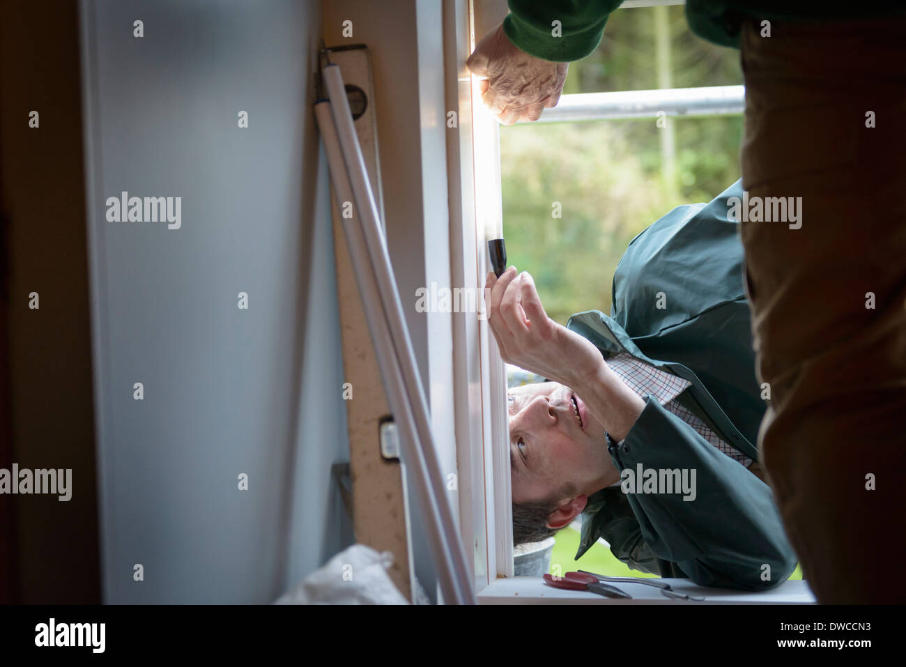 Father and son builders adjusting new window in house, close up Stock Photo