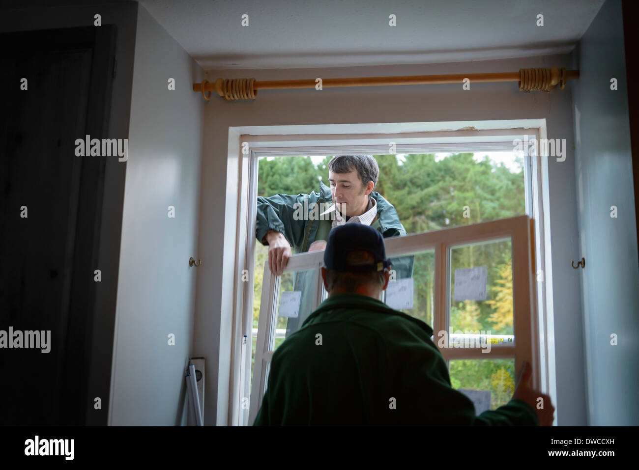 Father and son builders installing new window in house Stock Photo