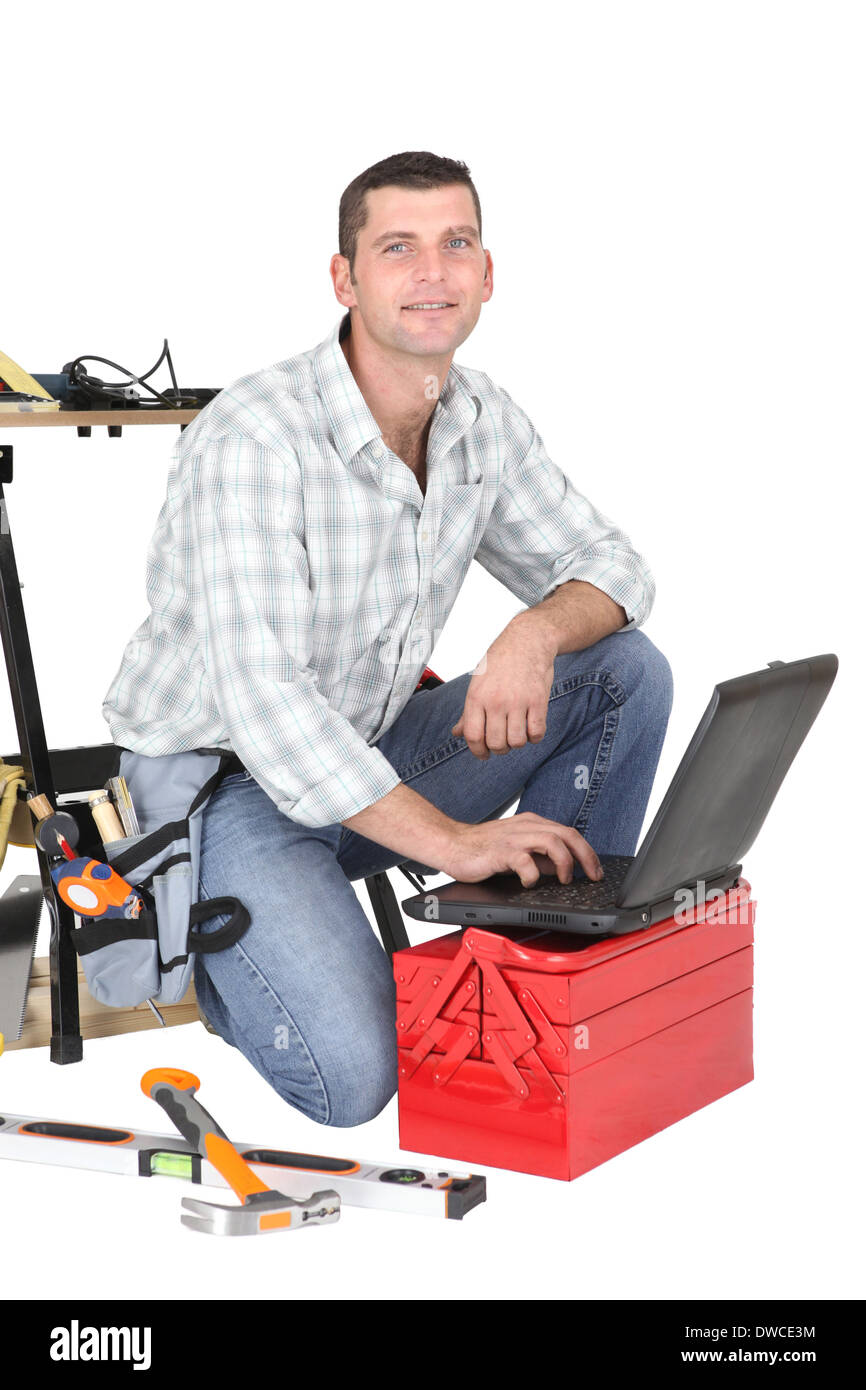 Handyman kneeling by laptop and tool kit Stock Photo - Alamy