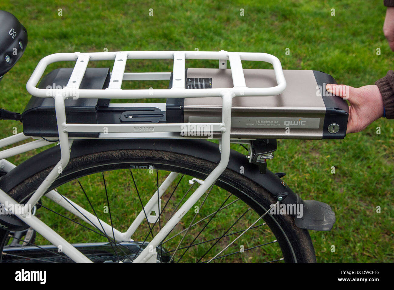 Man placing lithium-ion battery pack under rear carrier rack of pedelec / e-bike / electric bicycle Stock Photo