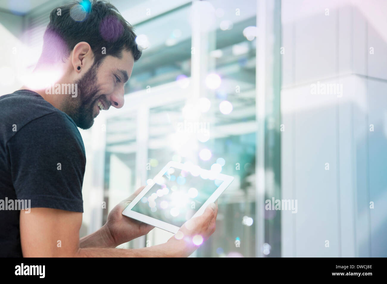 Mid adult man looking at lights coming from digital tablet Stock Photo