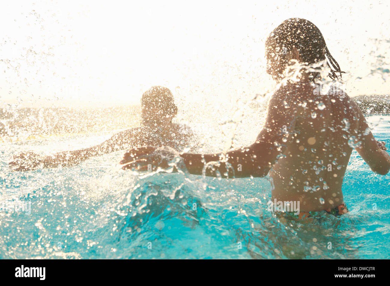 Couple having fun, splashing around in outdoor swimming pool Stock Photo