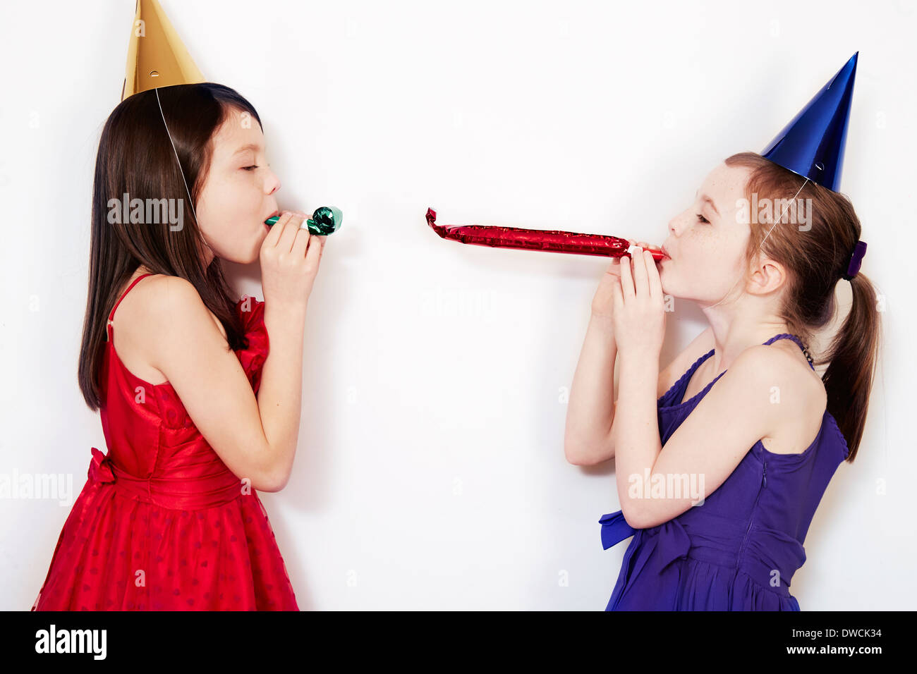Portrait of two girls blowing party blowers Stock Photo Alamy