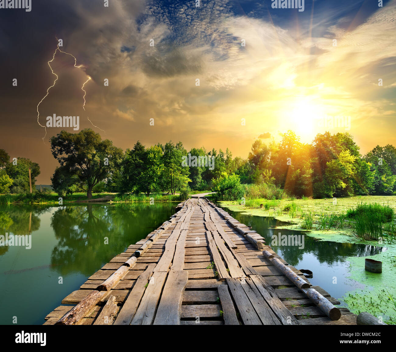 Lightning over a wooden bridge on a river Stock Photo