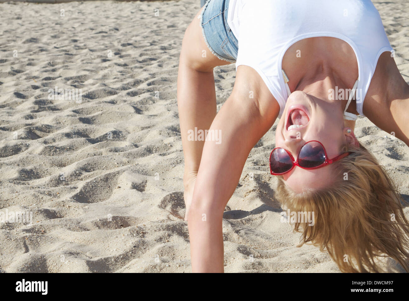 Close up of young woman bending over backwards on beach Stock Photo