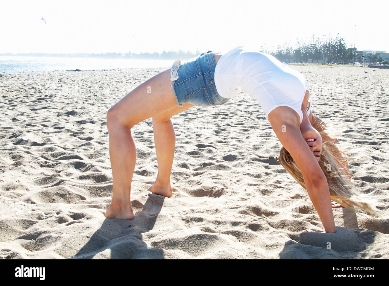 Young woman bending over backwards on beach, Melbourne, Victoria, Australia Stock Photo