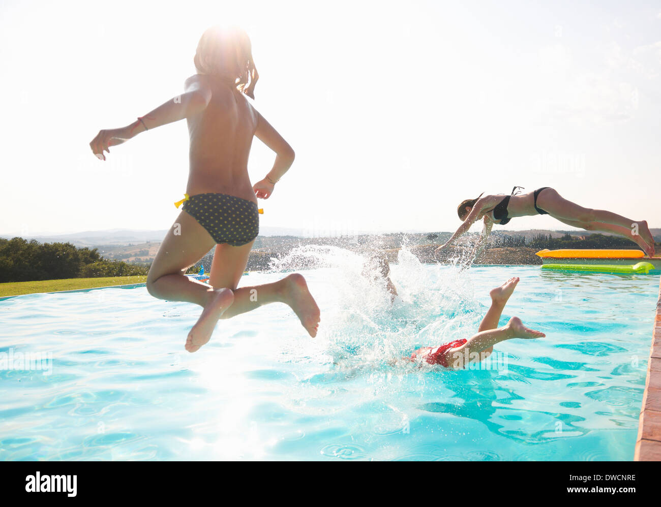 Three people jumping into swimming pool Stock Photo