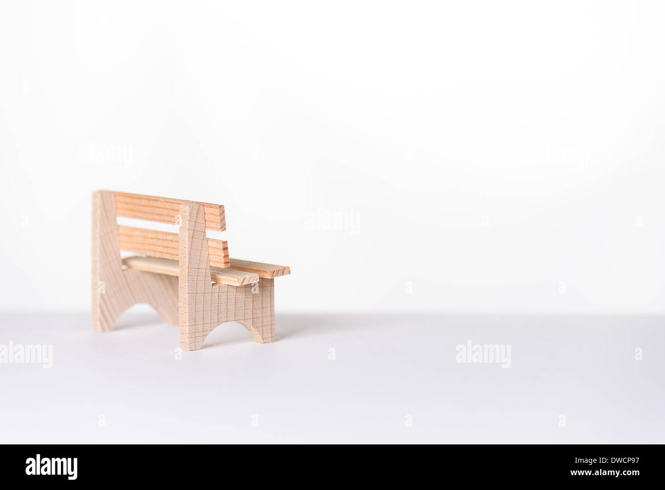 Small simple rustic vacant wooden bench placed to the side in an airy bright white minimalist room with copyspace Stock Photo