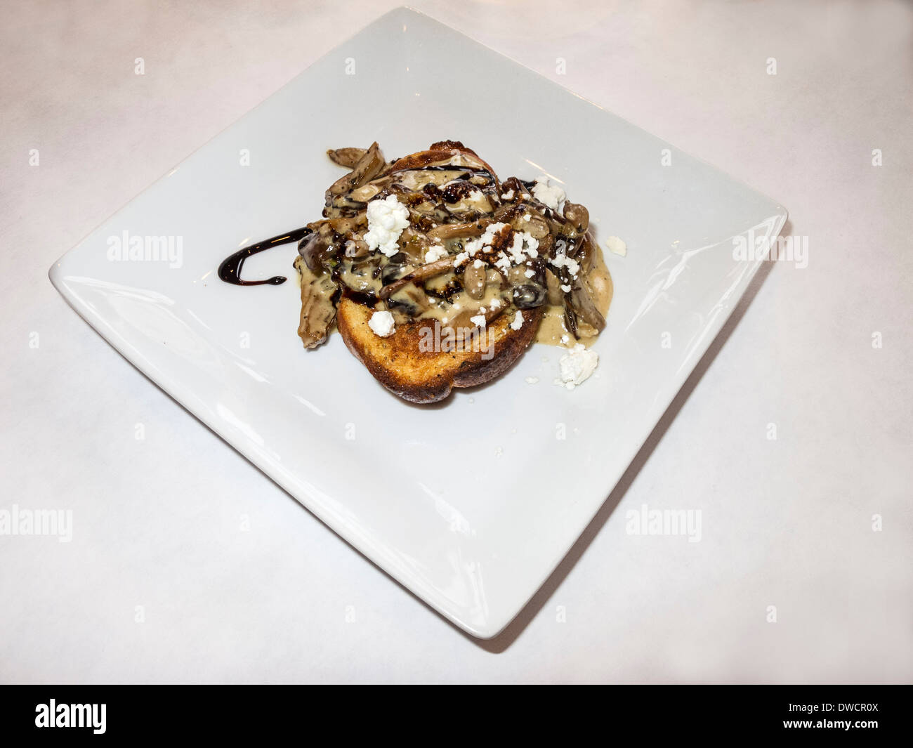 Mushroom taster featuring a wild mushroom saute over toast along with goat cheese, brandy cream and a balsamic reduction. Stock Photo