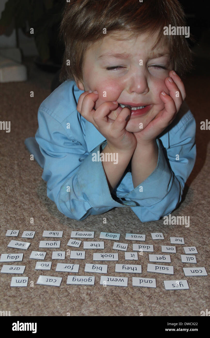 Reception aged boy crying trying to read key words, England, UK Stock Photo