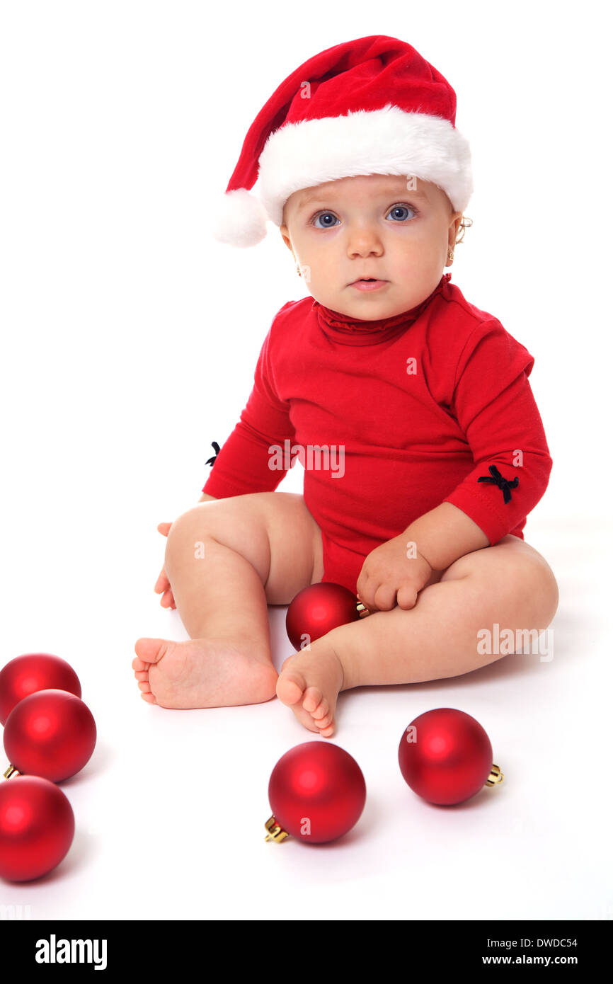 Baby girl wearing a Santa Claus hat, playing with red balls Stock Photo