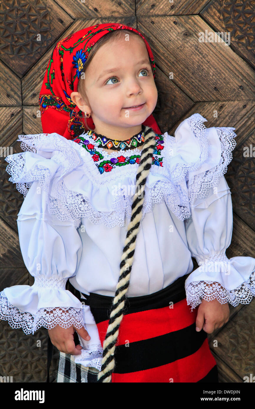 Little girl wearing Romanian traditional clothing and traditional wood door background Stock Photo